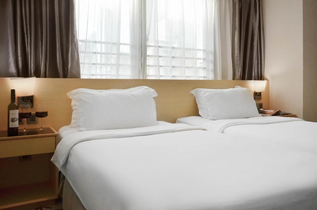 a bedroom with two beds with white pillows and a window at Eco Tree Hotel Sheung Wan in Hong Kong
