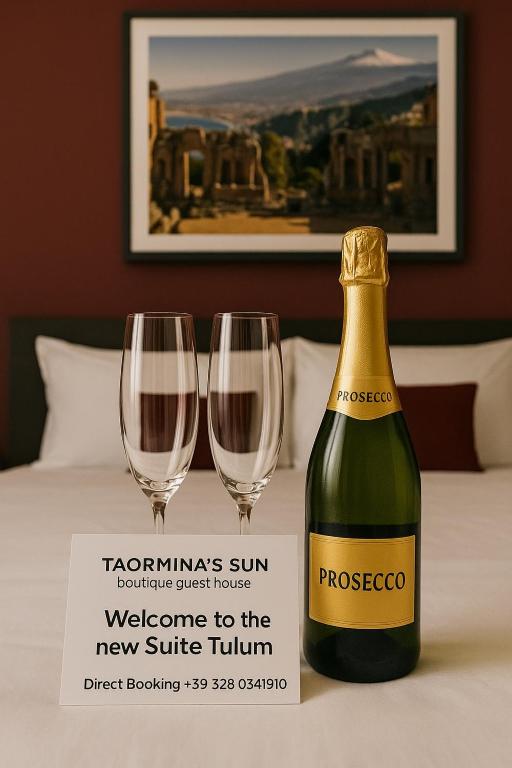 a bottle of wine and two wine glasses on a table at Taorminas Sun Central Boutique Guesthouse & Suites in Taormina