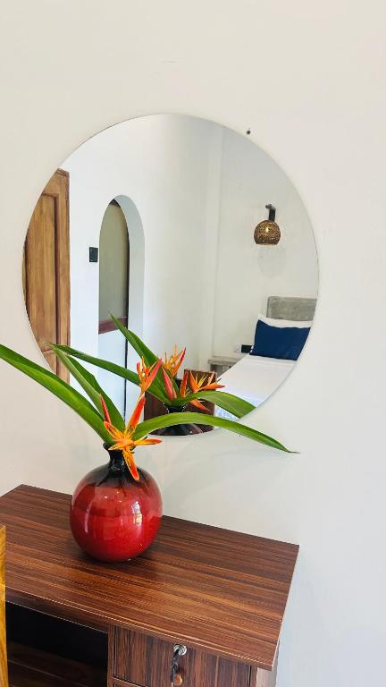 a red vase sitting on a wooden table with a mirror at Mango Hous in Ahangama Central
