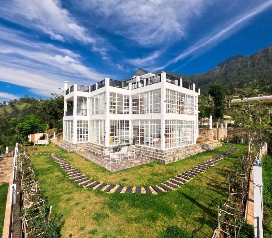 un gran edificio blanco en lo alto de un campo verde en Villa Rosaria, en Beragala