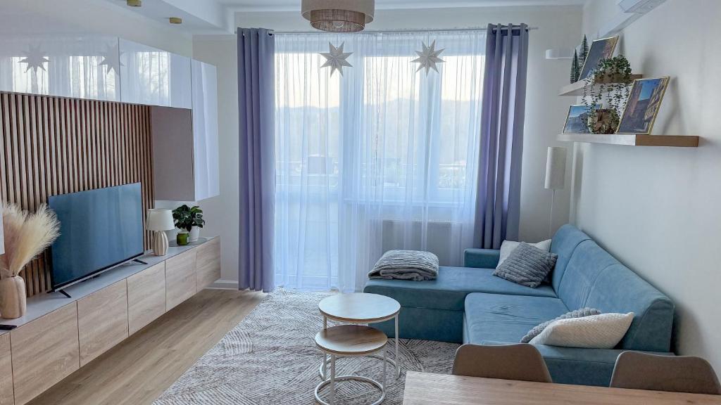 a living room with a blue couch and a tv at Apartament Ptasia Góra in Kłodzko