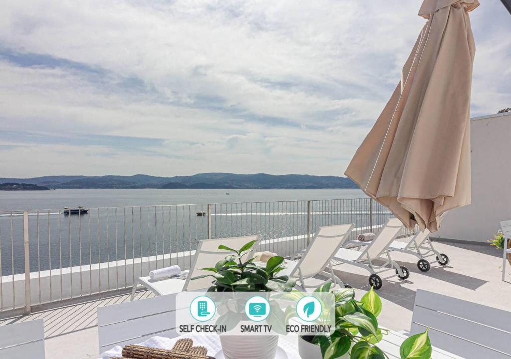 a patio with an umbrella and chairs on a balcony at Blue Ocean Deluxe in Portonovo