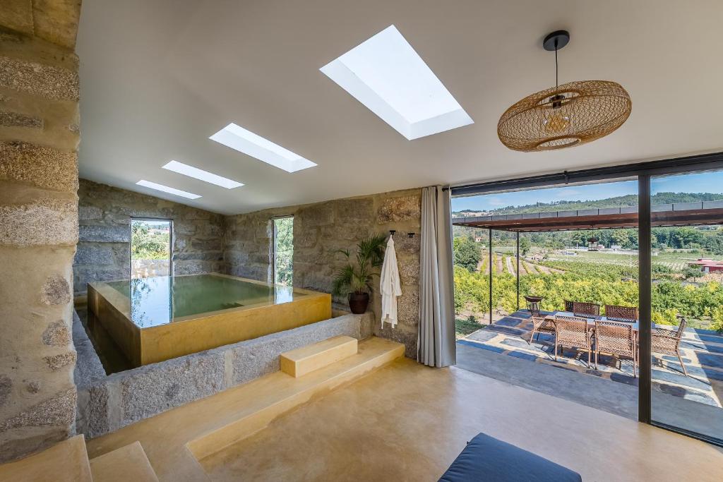 a bathroom with a tub and a large window at Lemon Villa with Private Indoor Heated Pool - Oporto Lemon Farm, near Porto in Valpedre