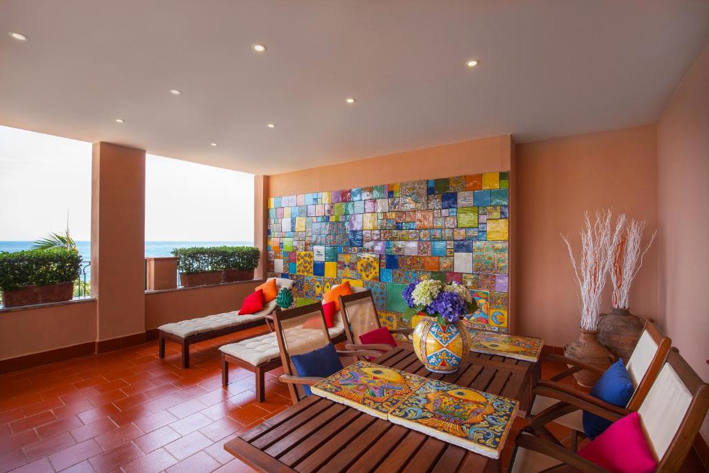 a living room with a table and chairs and a painting at Hotel Caparena in Taormina