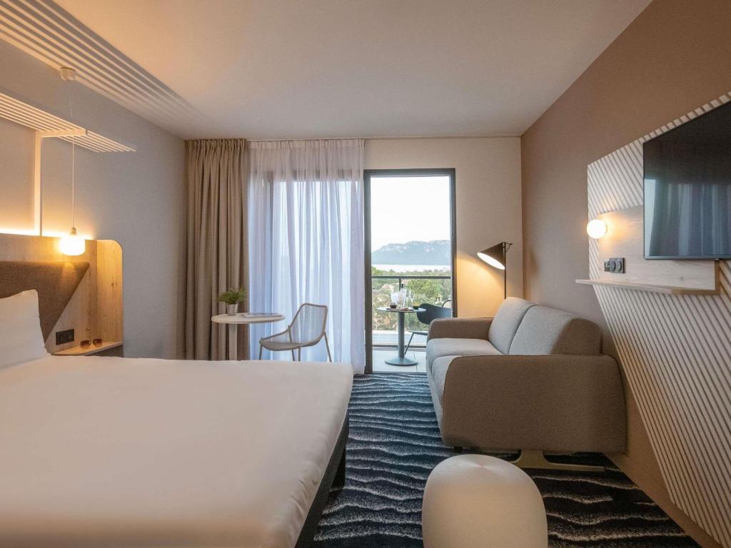 una habitación de hotel con una cama y un sofá en ibis Styles Porto Vecchio, en Porto Vecchio