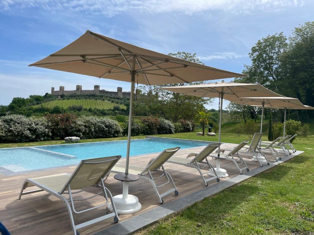 una fila di sedie e ombrelloni accanto a una piscina di Borgo Campassini, Monteriggioni a Monteriggioni