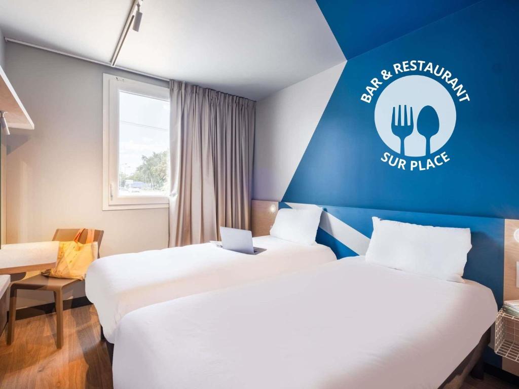 duas camas num quarto com uma placa na parede em ibis budget Nantes Nord Treillières em Treillières