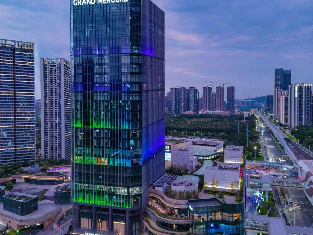um edifício alto com luzes verdes e azuis em uma cidade em Grand Mercure Shenzhen Guangming em Shenzhen
