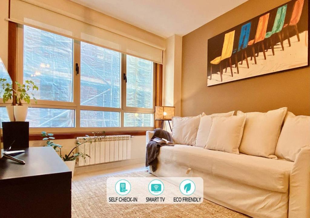 a living room with a couch and some windows at Orzan Beach Surf Apartment in A Coruña