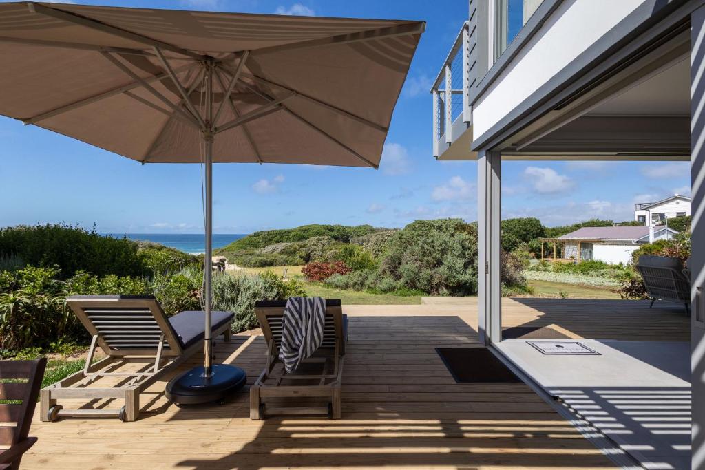 克乌尔伯姆斯特兰德Seagull View Sand的有两把椅子和一把遮阳伞的露台