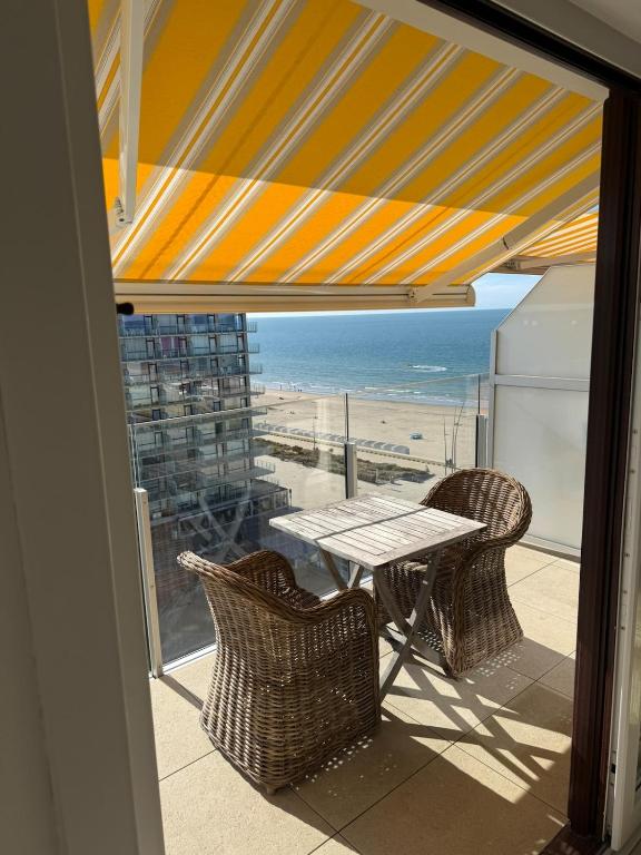a table and chairs on a balcony with a view of the beach at Residence Wembley with sea view in Middelkerke