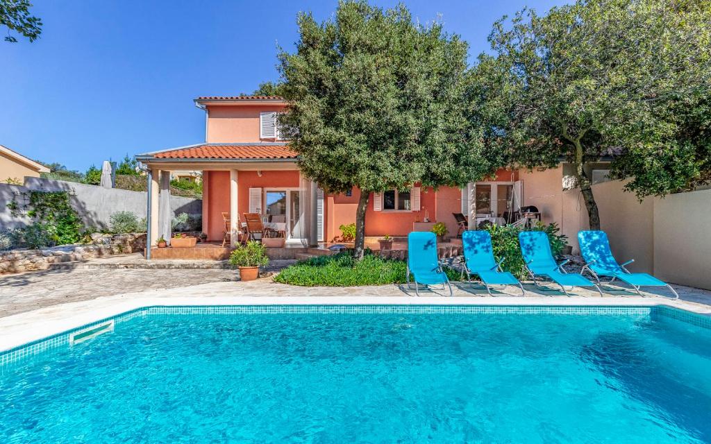 ein Pool mit blauen Stühlen und ein Haus in der Unterkunft Cozy holiday home Ella Nature with pool near the beach in Peroj