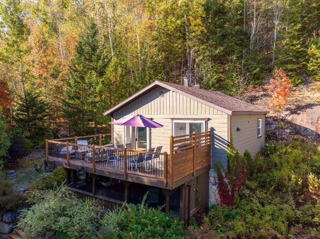 a house with a deck with chairs and an umbrella at Lakeside & Private dock - Le Suisse d-Entrelacs in Entrelacs