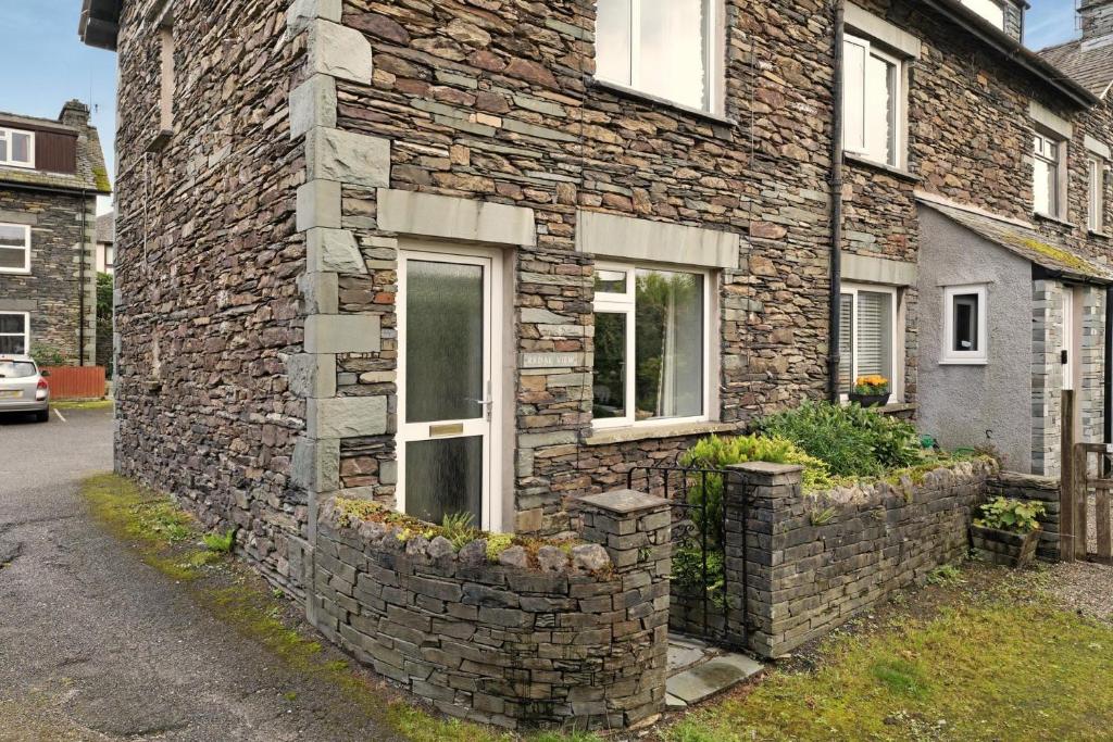 a stone building with two windows and two flower pots at Rydal View Cottage in Ambleside