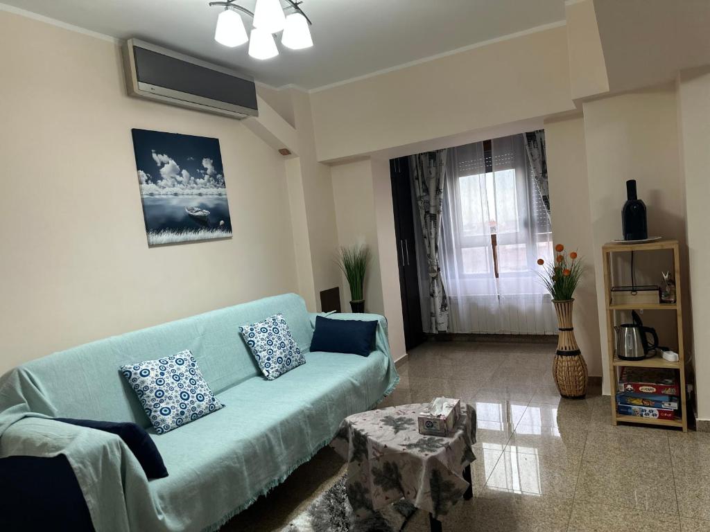 Una sala de estar con un sofá azul y una ventana. en Geany Apartament Ultracentral, en Craiova