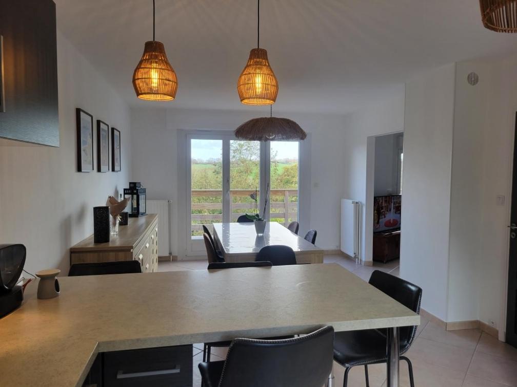 Una cocina y un comedor con mesa y sillas. en Belle maison proche de la mer, en Wimille