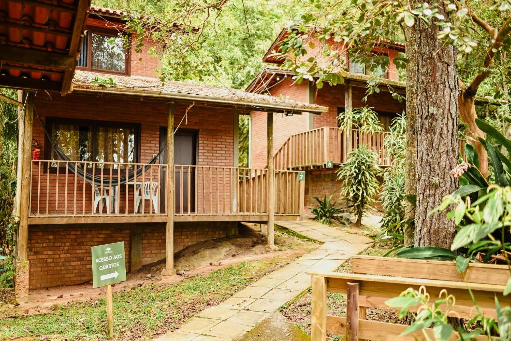 uma casa de tijolos com um deck e uma árvore em Pousada Nosso Bosque em Porto Belo