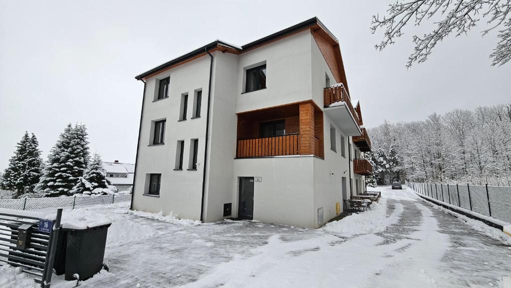 a white building with a balcony in the snow at Holiday Karpacz in Karpacz