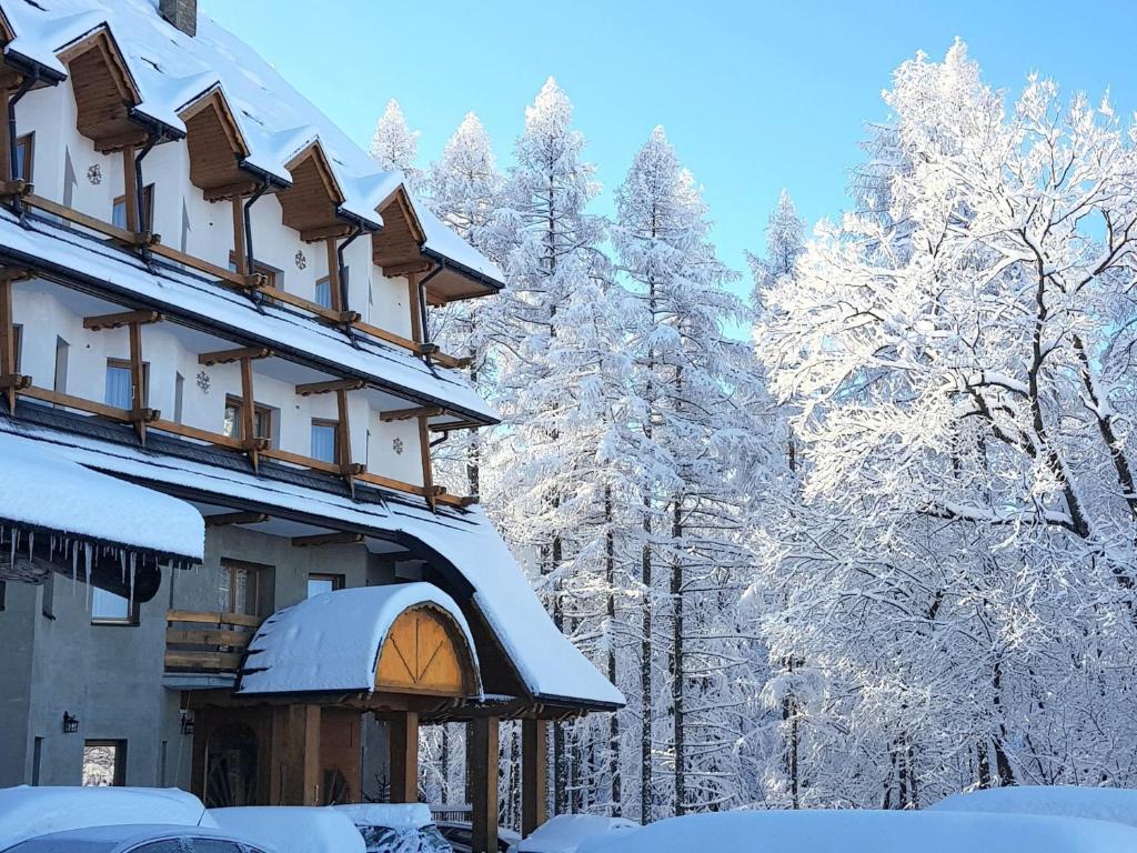 a building covered in snow with trees in the background at Ośrodek Wypoczynkowy "Zakopiec" in Zakopane