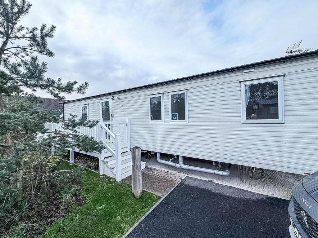 ein weißer Anhänger mit einer Treppe davor in der Unterkunft Spacious 8 Berth Caravan With Decking At Naze Marine In Essex Ref 17012Rd in Walton-on-the-Naze