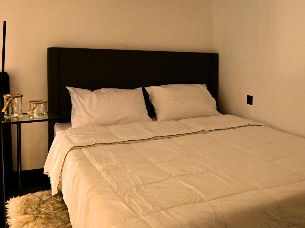 a bedroom with a large white bed with a black headboard at NEKTAR home in Latsídha