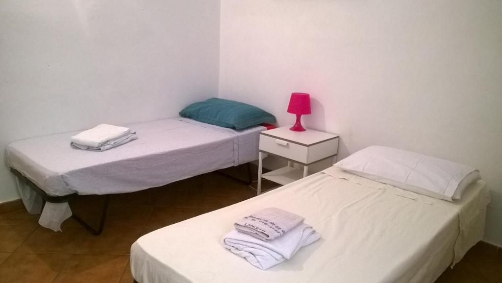 Habitación con 2 camas individuales y lámpara de color rosa. en Rita Room, en Florencia