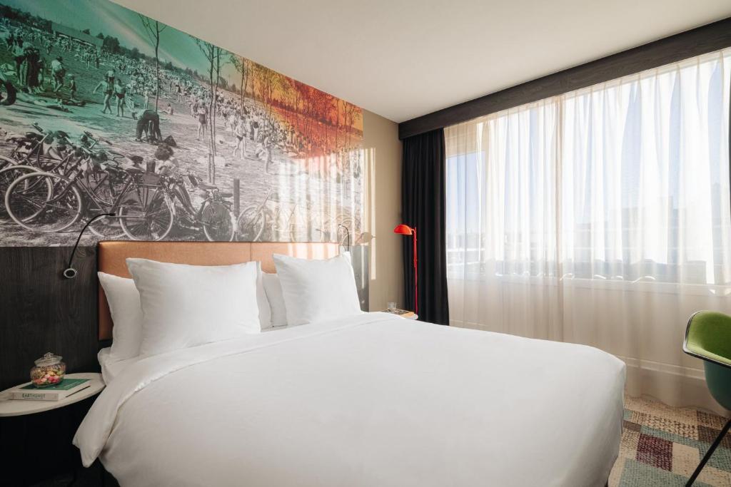 Un dormitorio con una gran cama blanca y una pintura en Leonardo Hotel Rotterdam Savoy, en Róterdam
