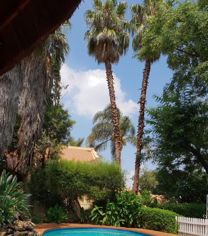 a resort with palm trees and a swimming pool at "O Sole Mio" Garden apartment in Bedfordview 12 minutes from OR Tambo International Airport in Bedfordview