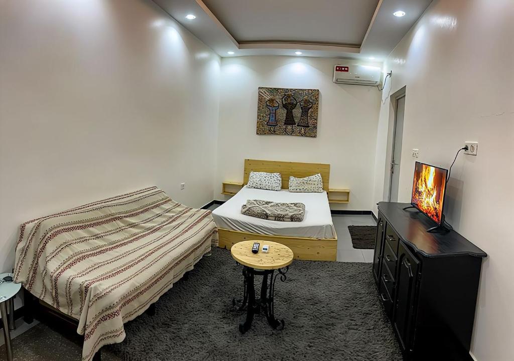 a room with two beds and a table and a television at Classimo in Dakar