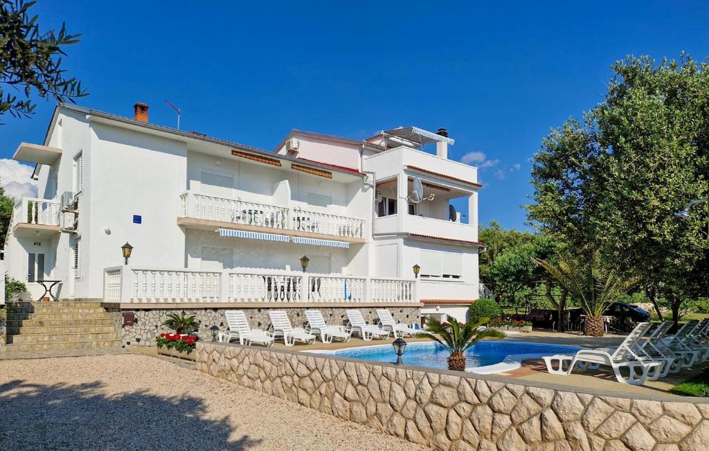 Stunning Apartment In Rab في Barbat na Rabu: مبنى ابيض كبير به مسبح وكراسي