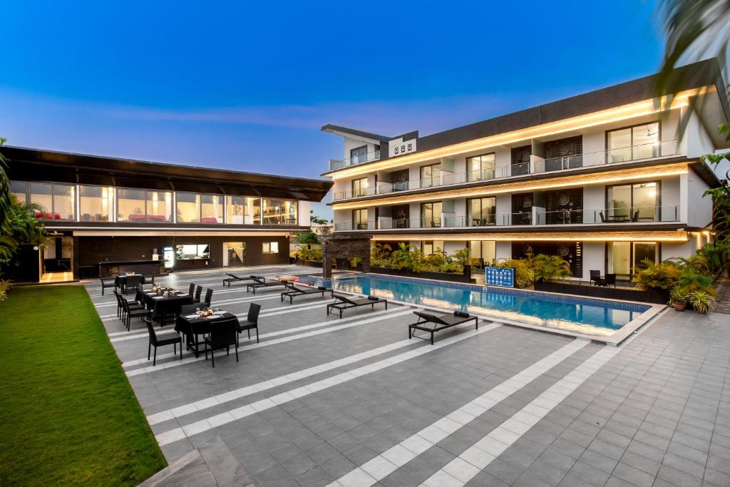 a resort with a pool and tables and chairs at Crystal Village in Nagoa-Bardez