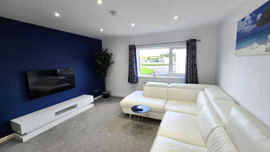 a living room with a white couch and a tv at Stepping Stones in Perranporth