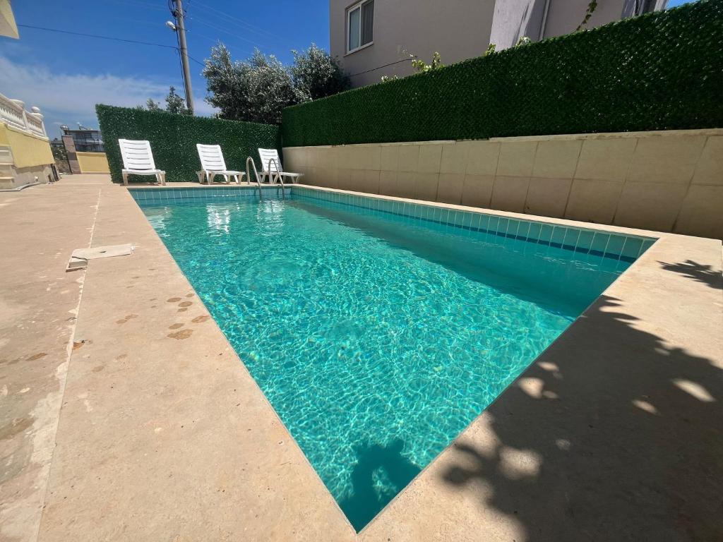 a swimming pool with two lawn chairs at ALTINKUMDA 12 Kişilik ÖZEL HAVUZLU VİLLA in Didim