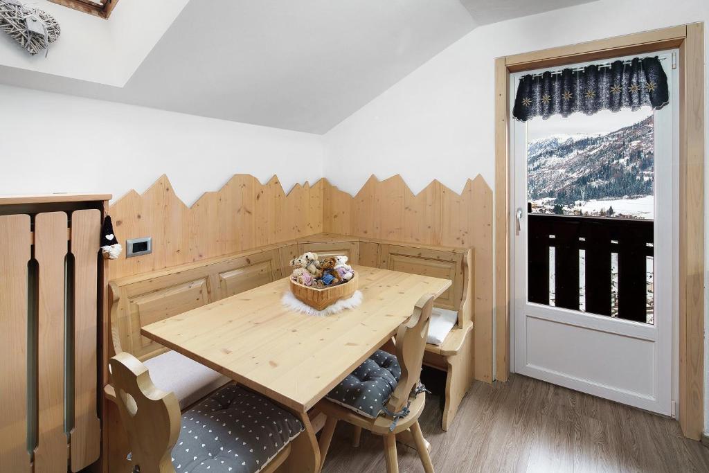 a wooden table and chairs in a room with a window at Appartamento Primavera 3 in Moena