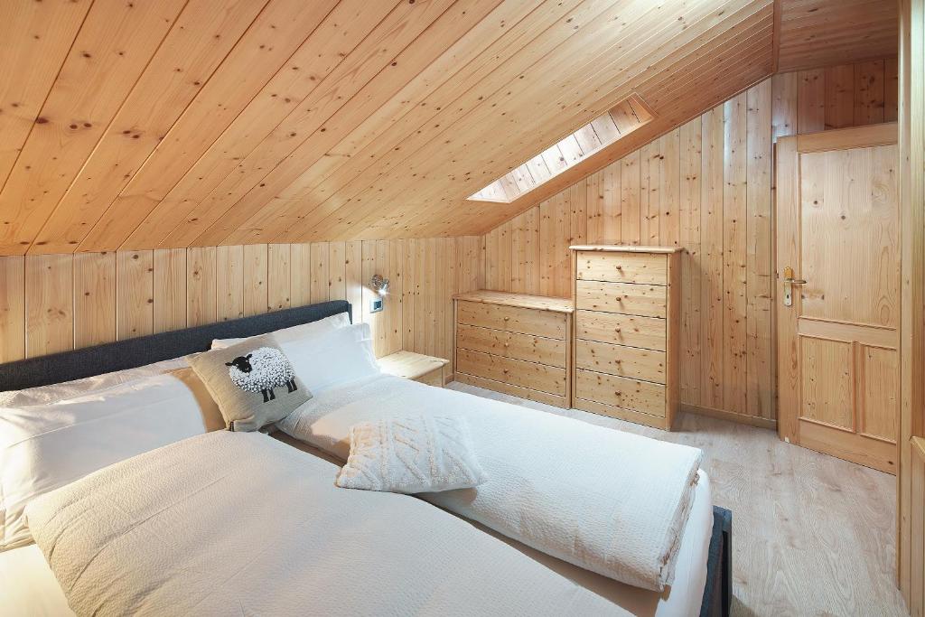 ein Schlafzimmer mit einem großen weißen Bett in einer Holzdecke in der Unterkunft Appartamento Primavera 3 in Moena