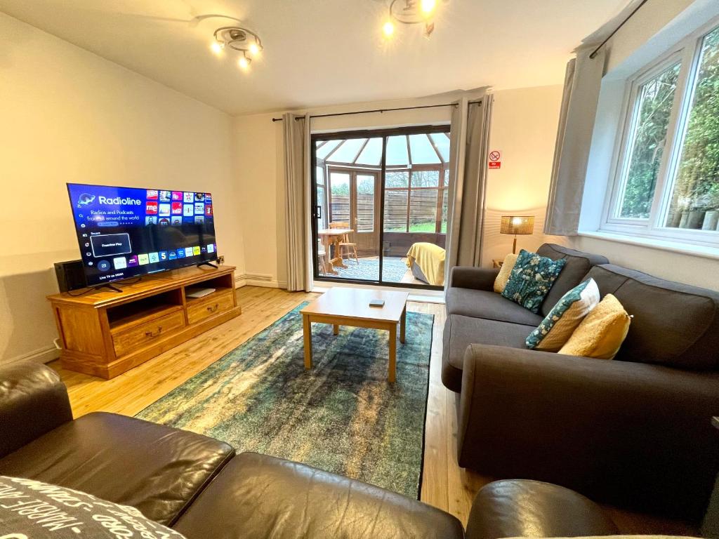 uma sala de estar com sofás e uma TV de tela plana em Large 5 bed detached house near Stansted Airport with Parking for 2 vehicles! Stansted Stays em Stansted Mountfitchet