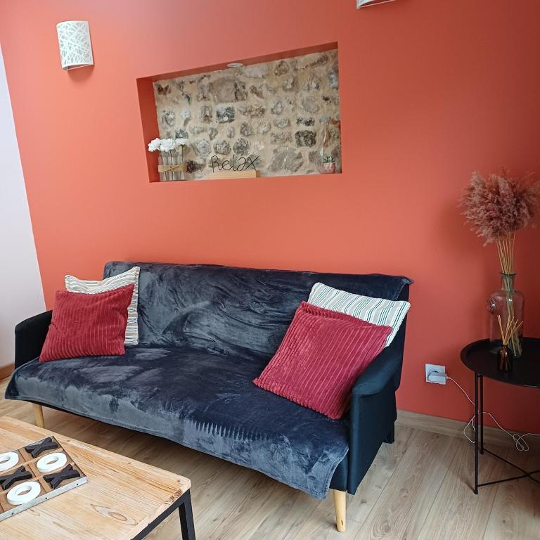 a blue couch in a living room with an orange wall at Le petit cauchois in Fécamp