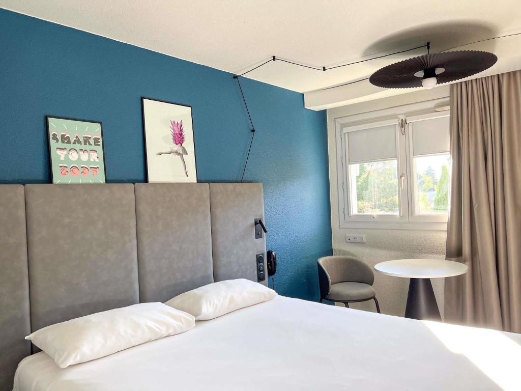 a bedroom with a bed and a table and a window at ibis Nîmes Ouest - A9 in Nîmes