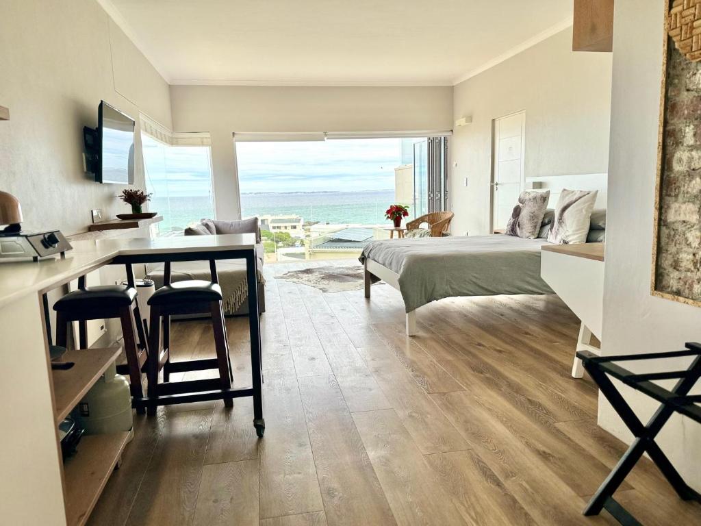 een slaapkamer met een bed en een bureau met uitzicht op de oceaan bij BB BEACH BAY QUALITY APARTMENTs in Cape Town