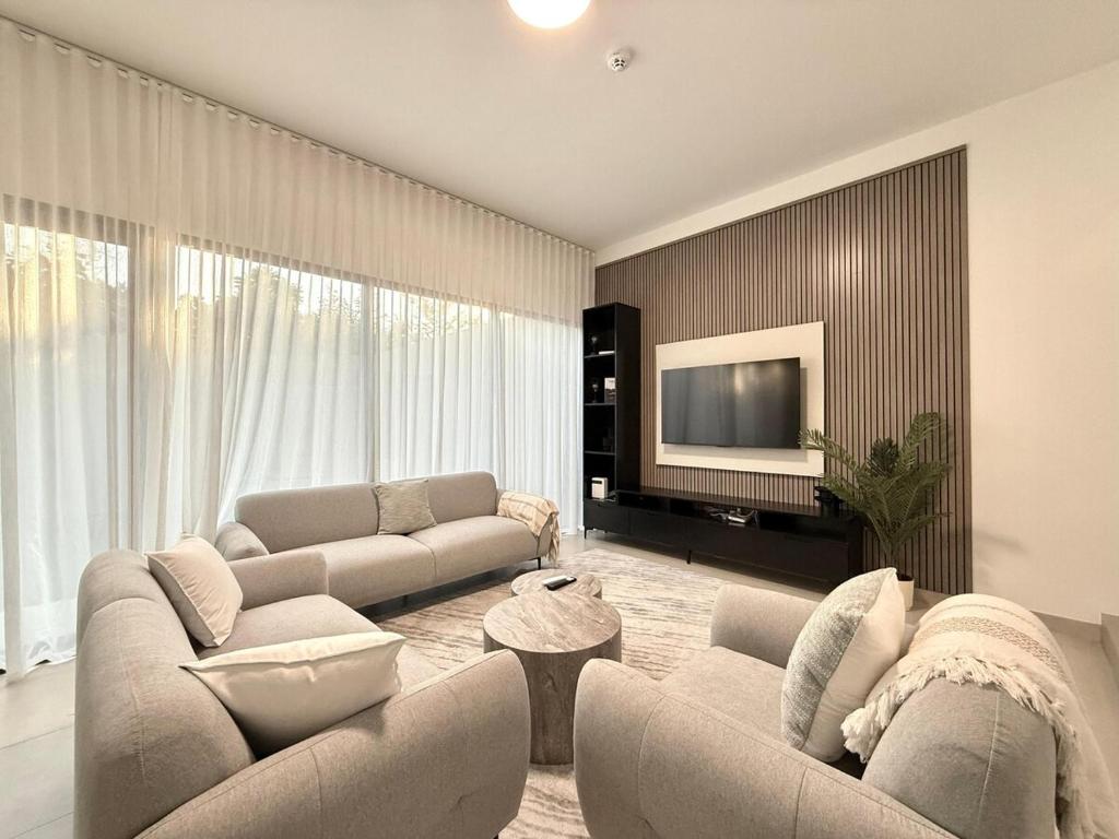 a living room with two couches and a television at Sahab - Masar 2BR Townhouse in Sharjah