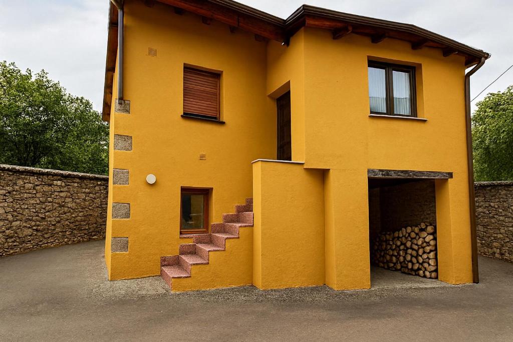Una casa amarilla con escaleras al costado. en La Casucha, en Caboalles de Abajo