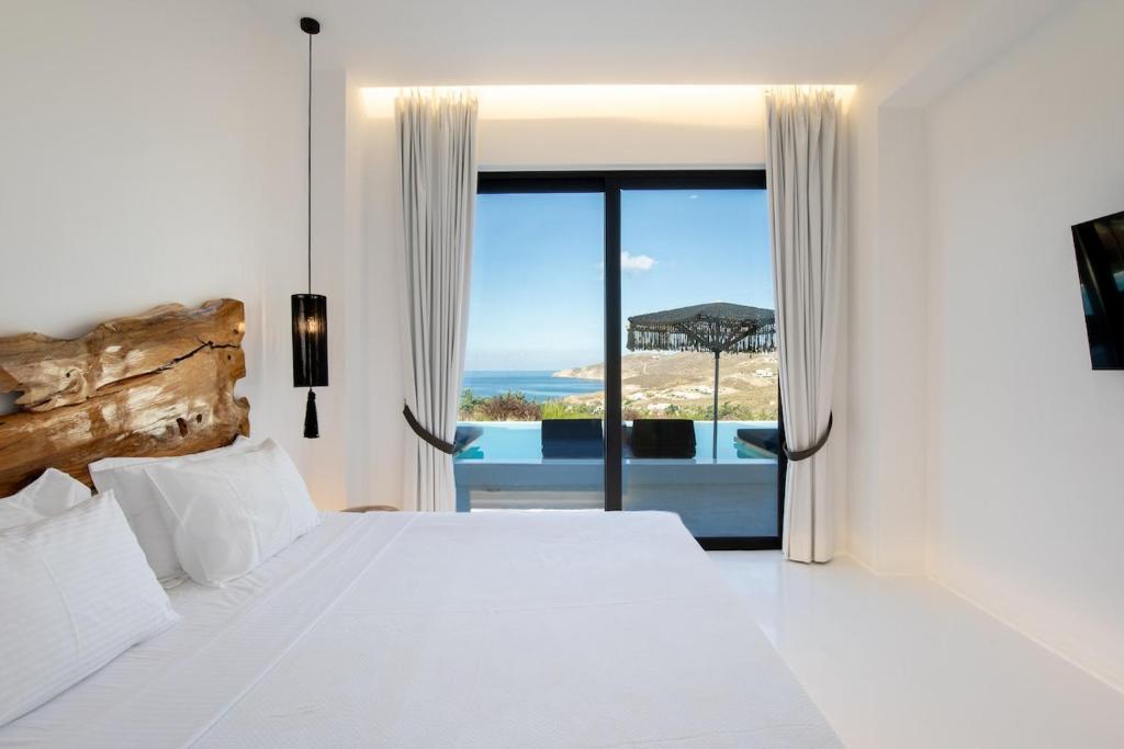 a bedroom with a bed and a view of the ocean at Aora Villa Ftelia Beach Mykonos in Panormos Mykonos