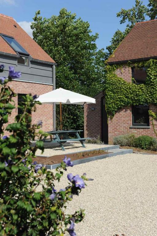 a picnic table with an umbrella next to a building at Gîte Fenêtres sur cour - Genappe in Genappe