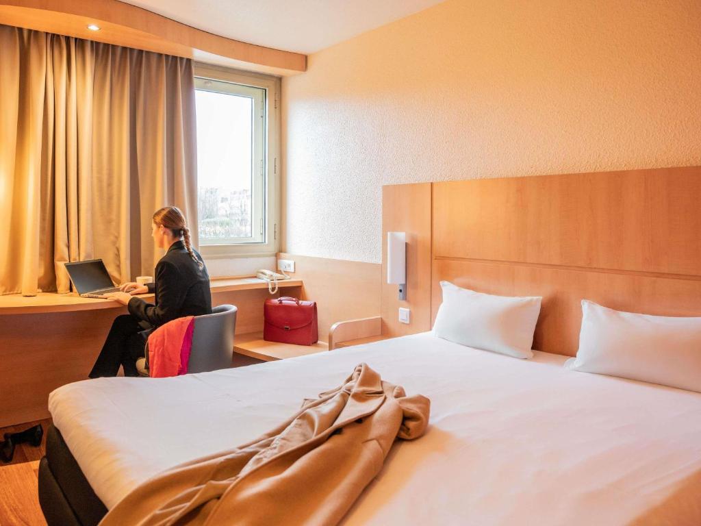 a woman sitting at a desk in a hotel room at ibis Nantes Centre Gare Sud in Nantes