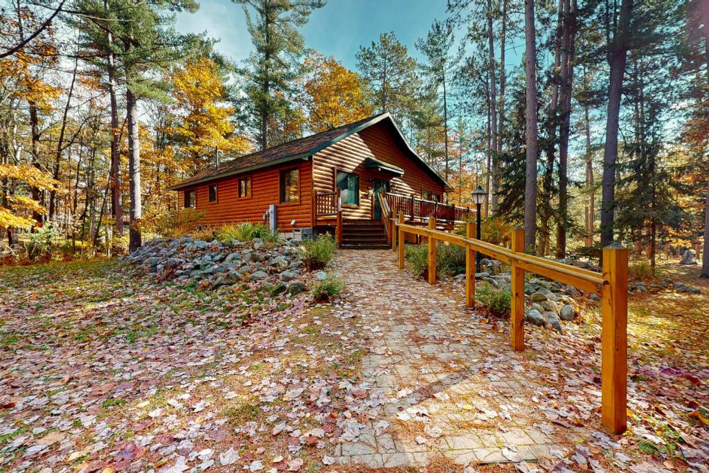 una baita di tronchi nel bosco con una recinzione in legno di Manitowish Mike’s a Manitowish Waters