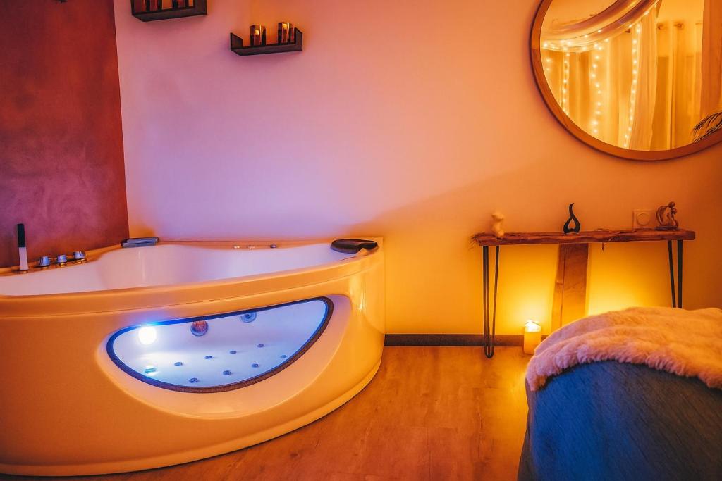 Una bañera en una habitación con un espejo grande. en Rendez-vous Secret, en Lunas