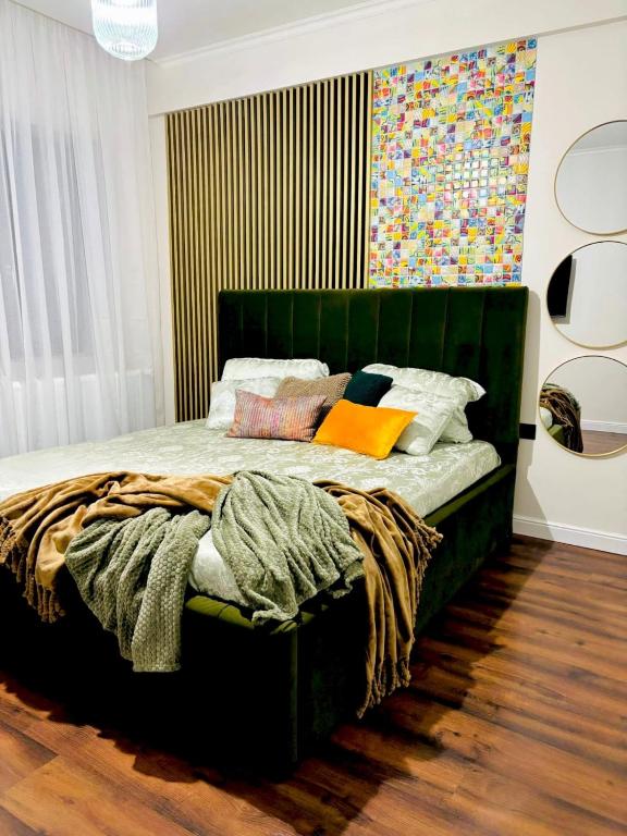 a bedroom with a green bed with colorful pillows at GZP Residence Lugoj 4 in Lugoj