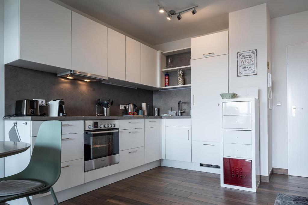 a kitchen with white cabinets and a table and a chair at Seepanorama in Unteruhldingen