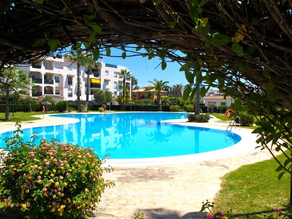 una gran piscina azul con un edificio en el fondo en 200m from the beach Apartment San Pedro Marbella, en Marbella