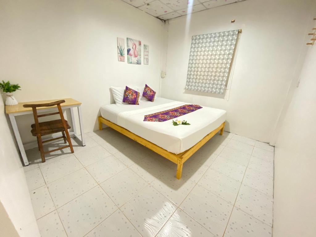 Un dormitorio con una cama, una mesa y una silla. en Baan Amila, en Phra Ae beach
